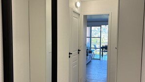 A hallway with white walls and doors, leading to a balcony with outdoor furniture. - Frisch renoviertes Apartment in traumhafter Lage (Saint-Raphaël)