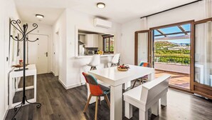 A modern kitchen with white cabinets, a dining table with chairs, and a balcony with a view of greenery. - Villa Elisa (Nerja)