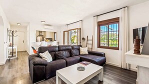 A modern living room with a leather sofa, a white coffee table, and a large window with curtains. - Villa Elisa (Nerja)