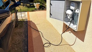 Une borne de recharge pour voitures, comprenant une boîte fixée au mur et une prise de courant.