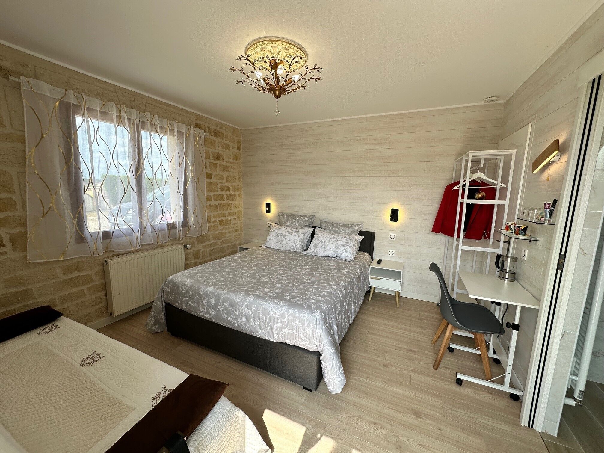 Une chambre à coucher comprenant un lit, un bureau, une chaise, un radiateur et une armoire.