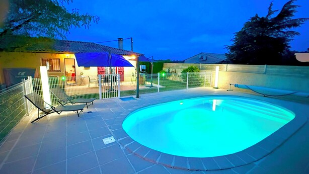 Une piscine avec une terrasse carrelée, un espace salon couvert et un patio clôturé.