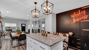 A modern kitchen with a central island, pendant lights, and a neon sign reading "Whiskey Business". - Modern rustic home near Bardstown top distilleries (Bardstown)