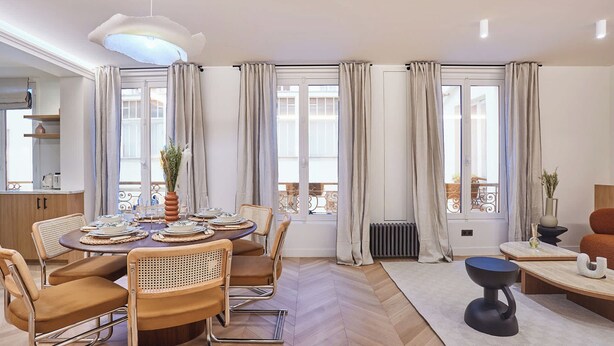 Un espace repas moderne avec une table ronde, des chaises et un vase central.