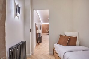 Een moderne slaapkamer met een bed, een radiator en een gang die leidt naar een eetgedeelte.