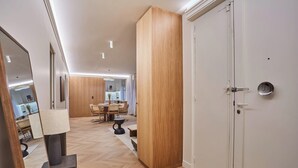 Un intérieur moderne avec un plancher en bois, un coin repas comprenant une table et des chaises, et une porte blanche ornée d’un miroir rond.