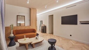 Un salon moderne avec un canapé, une table basse et un téléviseur à écran plat fixé au mur.