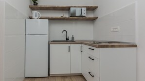 A compact kitchen with white cabinetry, a built-in microwave, a kettle, and a sink with a modern faucet. - 1 bedroom cozy apartment in Vir (Vir)