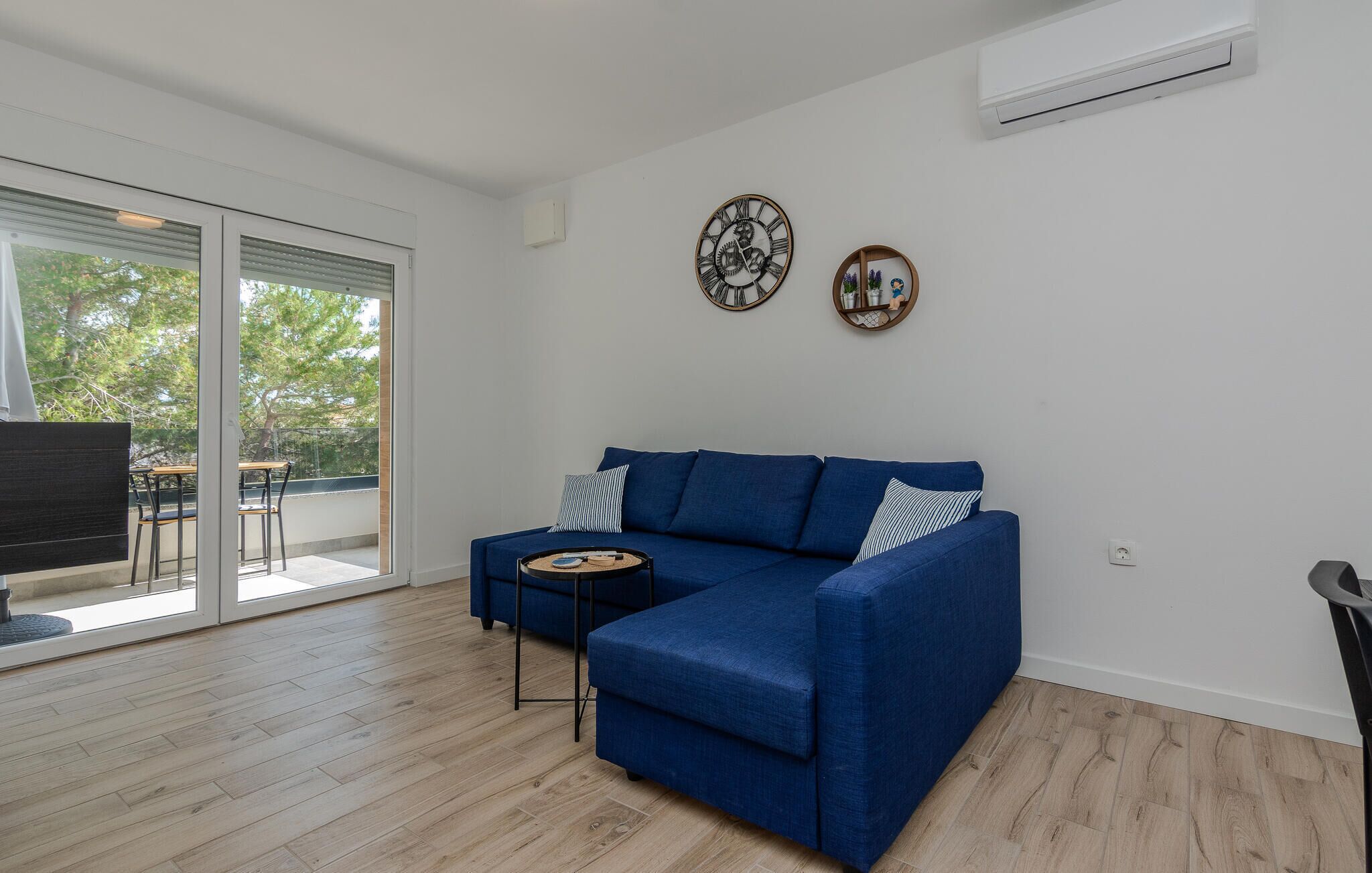 Een moderne woonkamer met een blauwe bank, een salontafel en twee wandklokken.