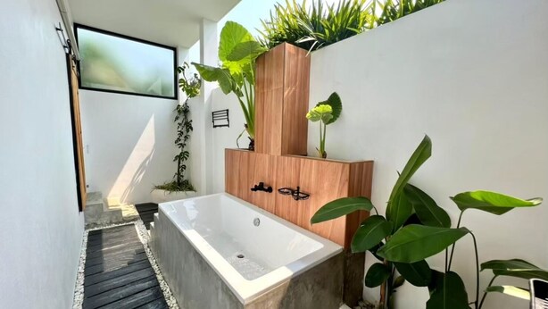 A modern bathroom with a freestanding bathtub, wooden paneling, and various plants. - The Estretto Resort (Wiang Chiang Rung)