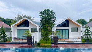 A modern resort with two white buildings, a swimming pool, and tropical plants. - The Estretto Resort (Wiang Chiang Rung)