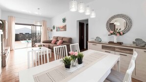 A modern living room with a dining area, white furniture, and a view to the outside. - Villa Elma (Yaiza)
