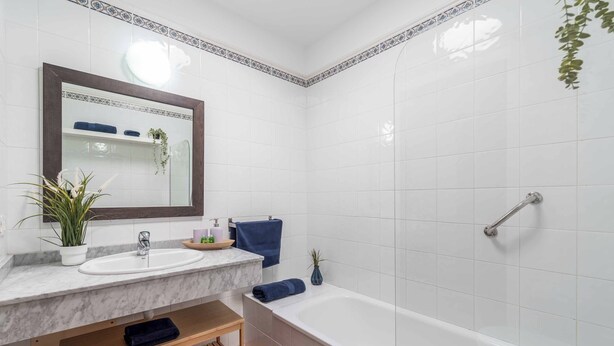 A bathroom with a marble sink, a bathtub, and a mirror with a decorative border.