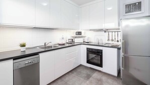 A modern kitchen with white cabinets, a dishwasher, a microwave, a toaster, and a refrigerator. - Villa Elma (Yaiza)