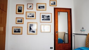 Ein Schlafzimmer mit einem Bett, einer Holztür und einer Wand mit gerahmten Fotografien.
