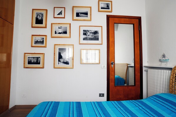 Ein Schlafzimmer mit einem Bett, einer Holztür und einer Wand mit gerahmten Fotografien.