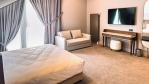 Una camera d'albergo moderna con un letto grande, una scrivania, una sedia, una televisione e un'ampia finestra con tende.