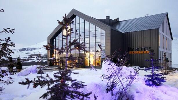 Un hotel moderno con una grande facciata in vetro, un tetto spiovente e un cartello con la scritta "HOTELS ERCIYES".