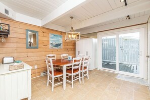 Een eethoek met een houten wand, witte kastjes, een houten tafel en stoelen.