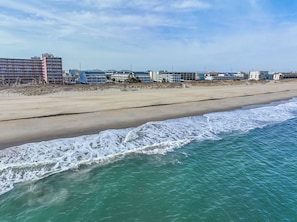 Een strand met een zandstrand en een gebouwencomplex op de achtergrond.
