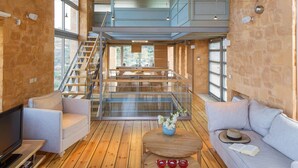 A spacious interior with a wooden floor, a staircase leading to an upper level, and a seating area with a sofa and a coffee table. - Chania Olea Villa - Breathtaking Summer Getaway (Chania)