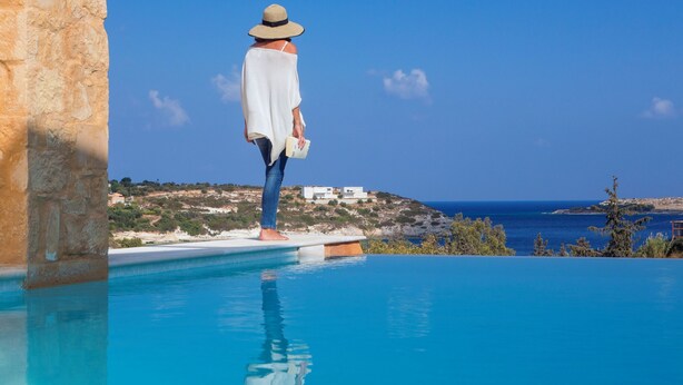 A person standing at the edge of a pool with a view of the sea and a hillside in the background. - Chania Olea Villa - Breathtaking Summer Getaway (Chania)
