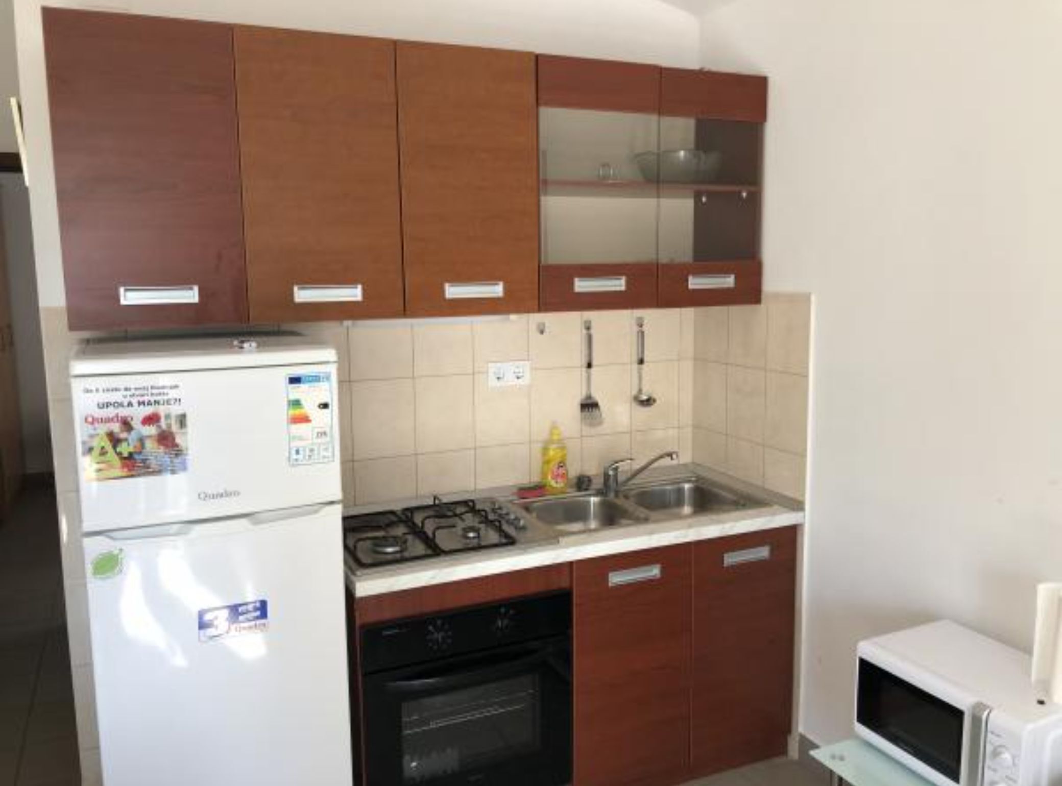 A compact kitchen with a refrigerator, stove, oven, and microwave.