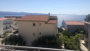 A coastal residential area with buildings featuring red-tiled roofs and balconies. - Apartmani Villa Borzic (Omis)