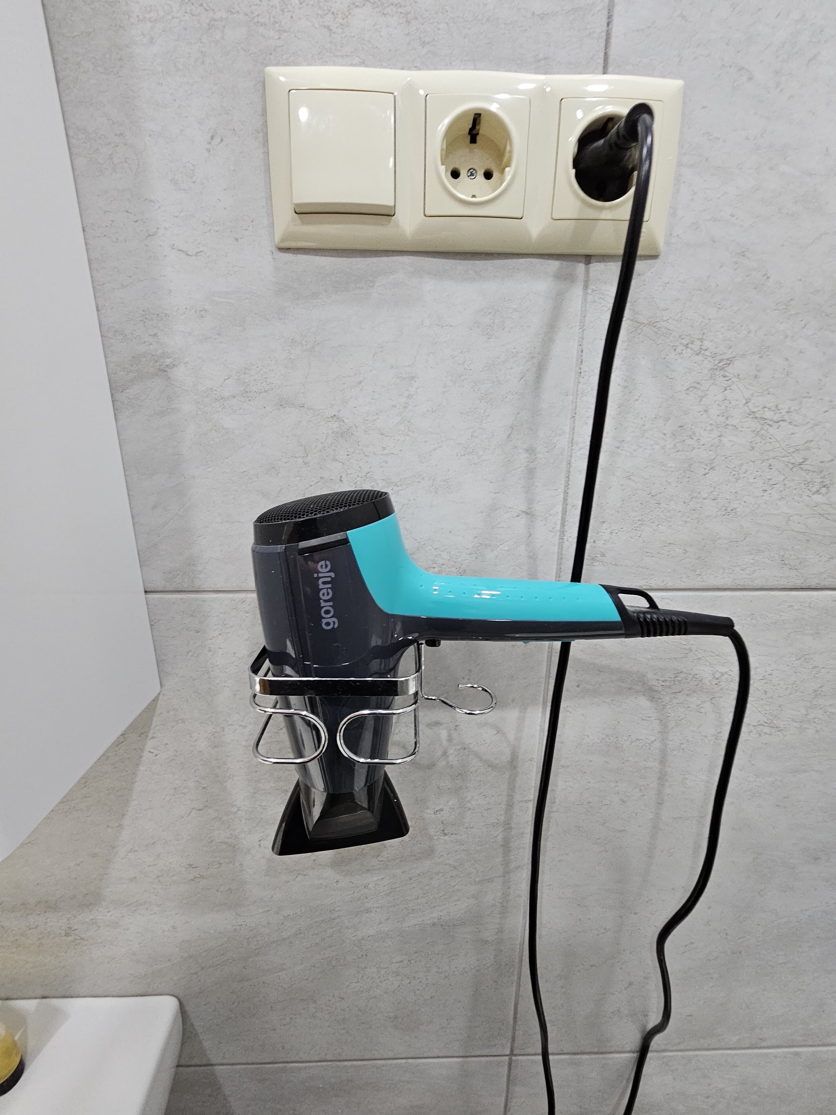 A hair dryer with a cord plugged into a wall socket.