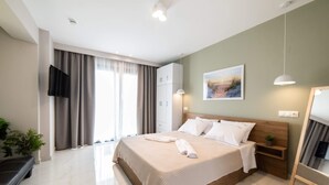 Een moderne slaapkamer met een groot bed, een flatscreen televisie, een kledingkast en een raam met gordijnen.