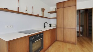 Moderni keittiö, jossa on puiset kaapit, sisäänrakennettu uuni, pesuallas ja työtaso.