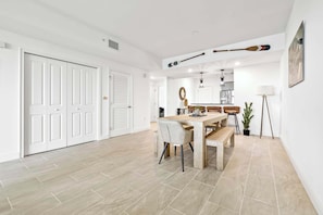 Un grand espace dédié à la salle à manger, avec une table et des chaises en bois, un banc, une plante en pot et une lampe.