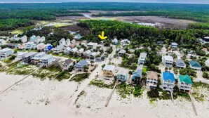 Luftaufnahme einer Küstenwohngegend mit Häusern, einem Strand und einer bewaldeten Landschaft.