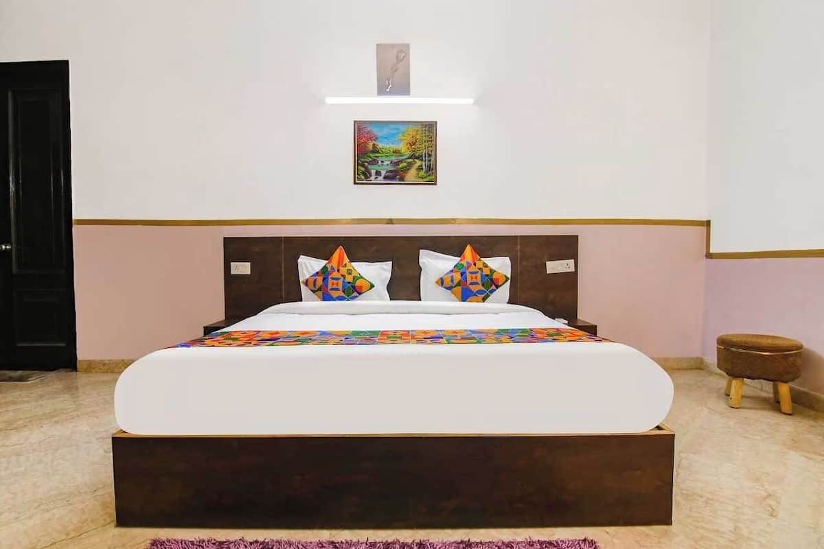 A bedroom with a large bed, a wooden headboard, and a small stool.