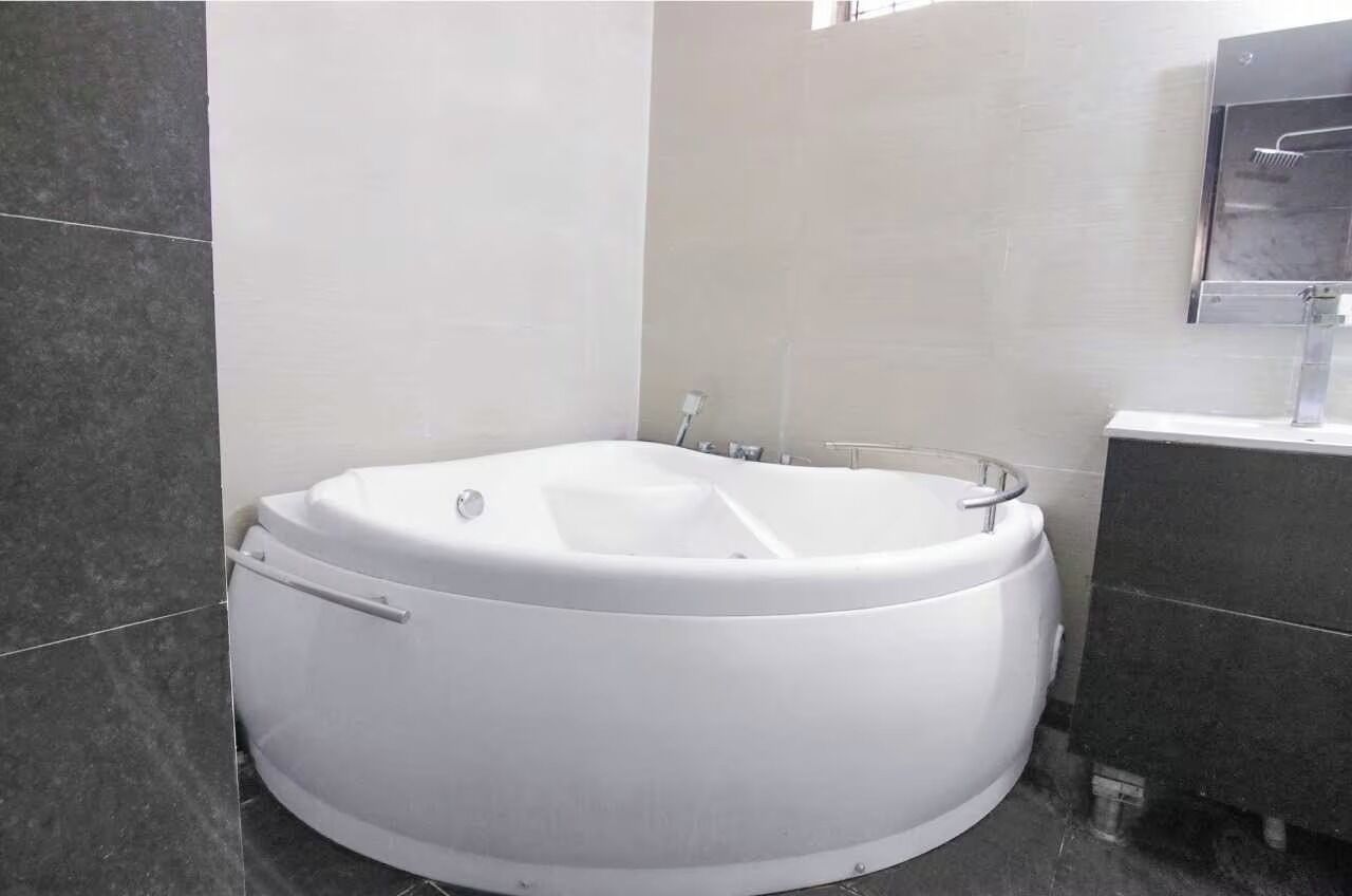 A modern bathroom with a freestanding bathtub, a vanity with a mirror, and tiled walls.