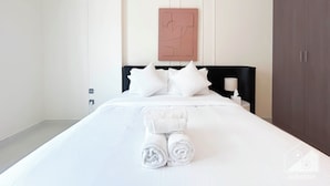 Een hotelkamer met een net opgemaakt bed, een kunstwerk aan de muur en een kledingkast.