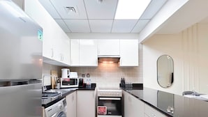 Een praktische keuken met een wasmachine, magnetron, oven en een spoelbak.