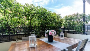 An outdoor dining area with a wooden table, two white lanterns, and a vase with flowers. - VivimiHome-Esclusivo loft con terrazzo (Milan)