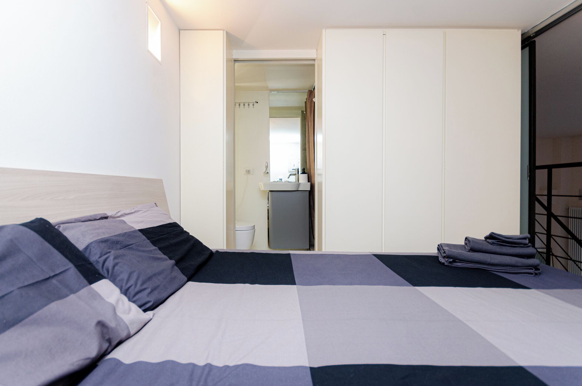 A bedroom with a bed, a wardrobe, and a bathroom visible through an open door.