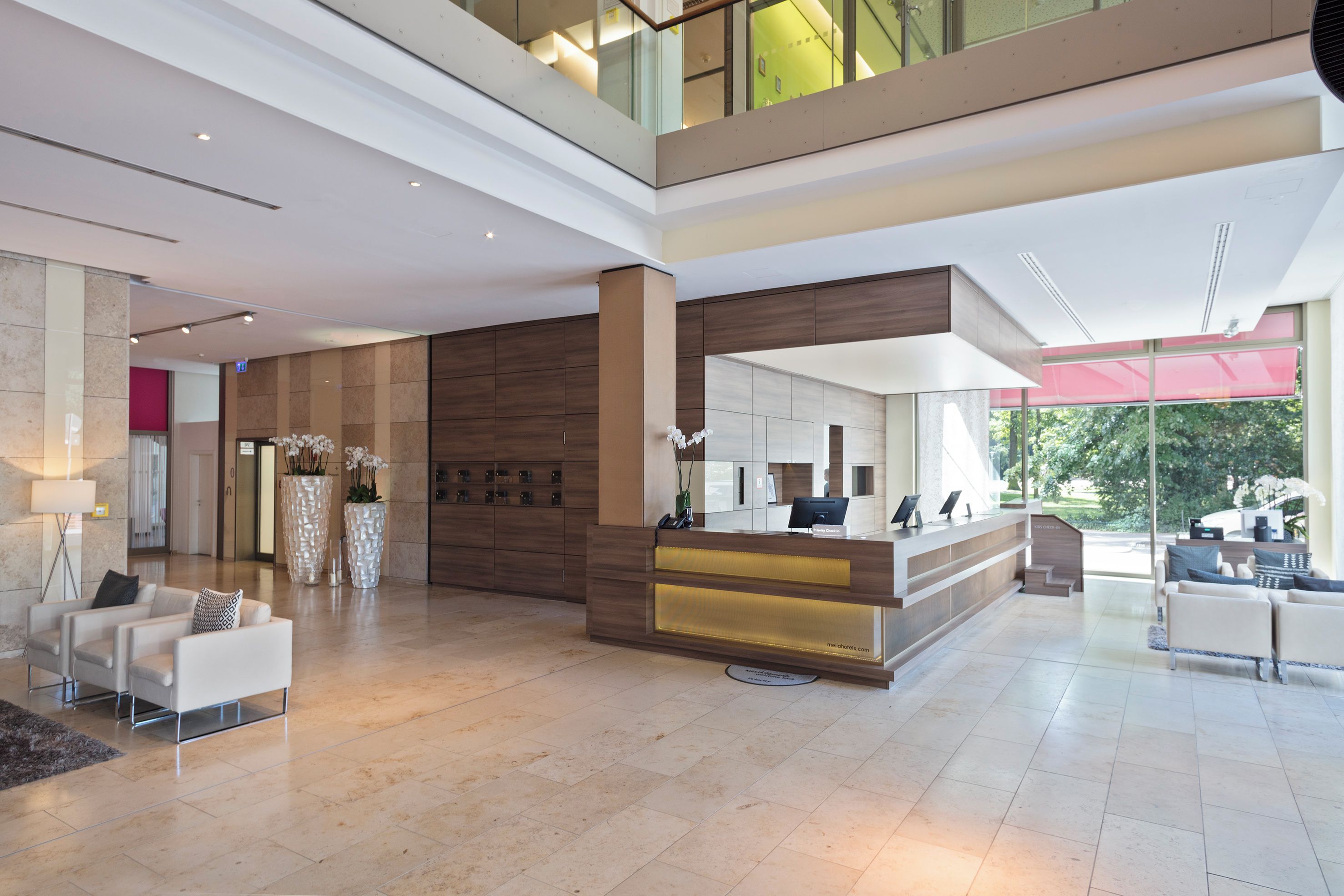 A spacious lobby with a reception desk, seating area, and a view of the outdoors.