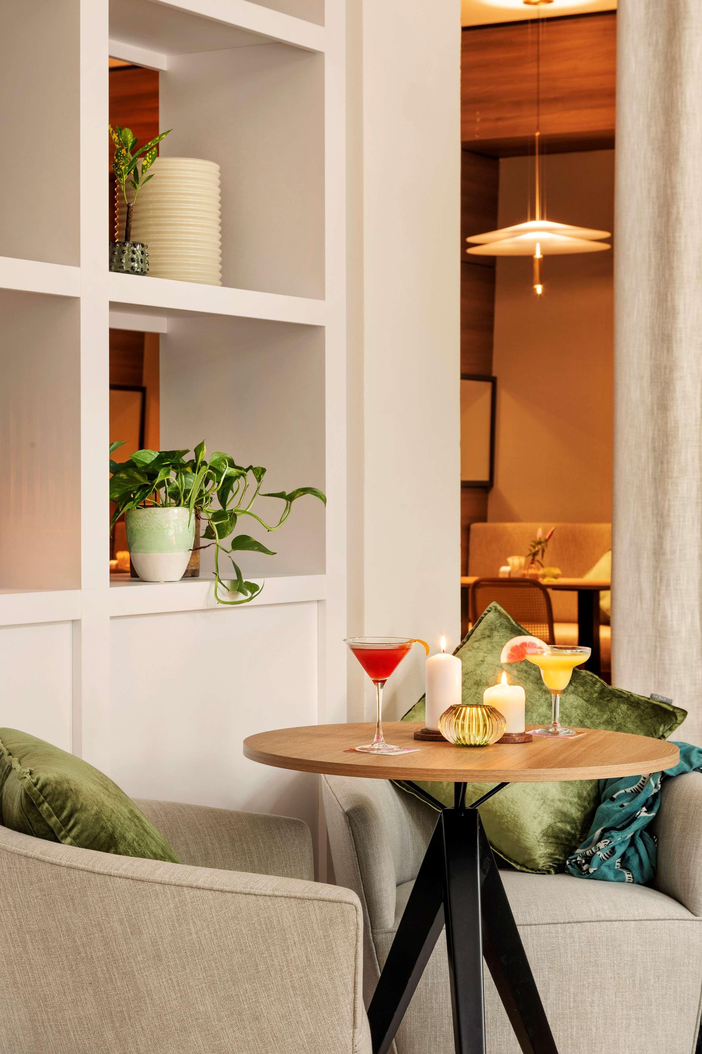 A modern living room with a round wooden table, two sofas, a bookshelf, and a hanging light fixture.
