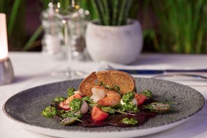A plate of food with shrimp, tomatoes, and greens, served on a textured plate.