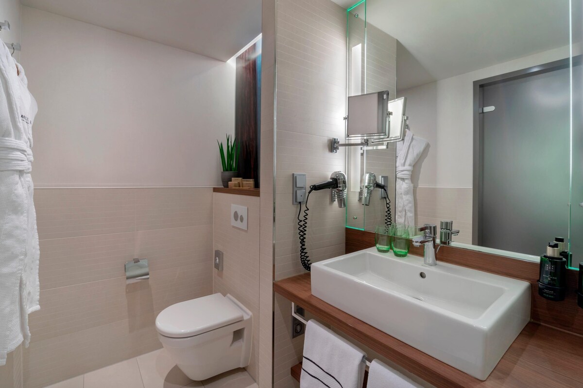 A modern bathroom with a toilet, a sink with a mirror, and a shower area.