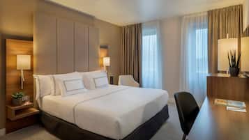 Una habitación de hotel con una cama grande, dos mesitas de noche con lámparas, un escritorio y una silla.