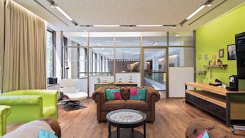 Una sala moderna con un sofá marrón, un sillón verde y una mesa de centro redonda.