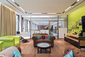 A modern living room with a brown sofa, green armchair, and a round coffee table. - Meliá Düsseldorf (Düsseldorf)
