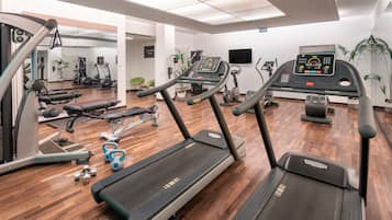 Un gimnasio con cintas de correr, máquinas de pesas y pesas libres.