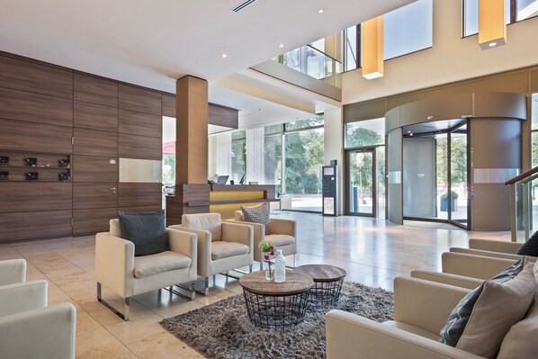 Un vestíbulo moderno con una recepción, zona de estar y ventanas amplias.