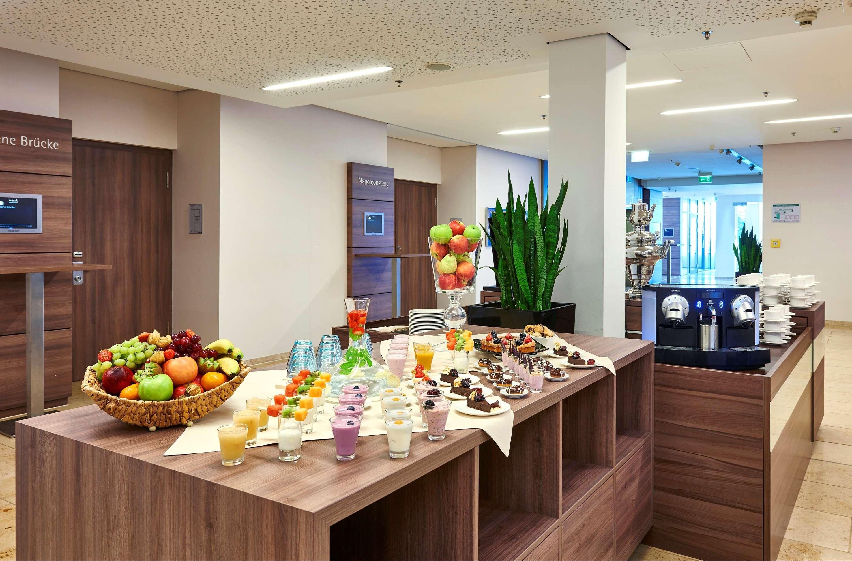 A buffet area with a variety of fruits, beverages, and desserts.