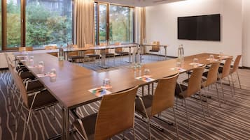 Ein Konferenzraum mit einem langen Tisch, Stühlen und einem großen Fenster mit Vorhängen.